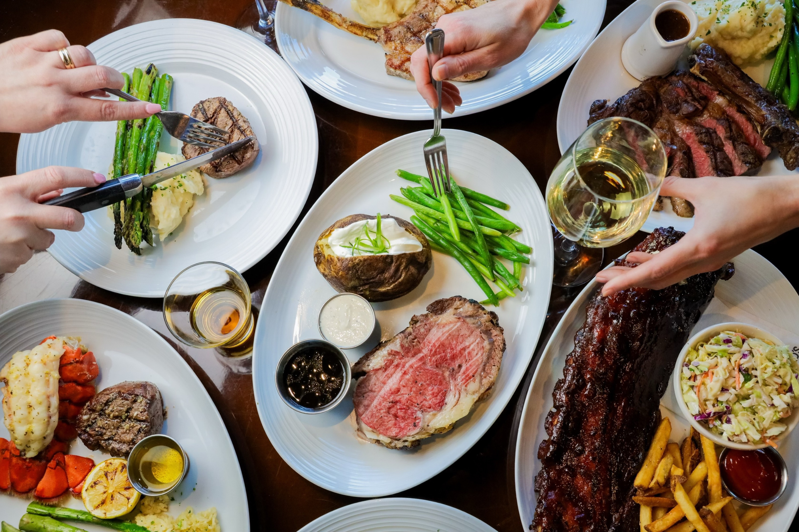 Overhead spread of dishes on table top with hands grabbing in.